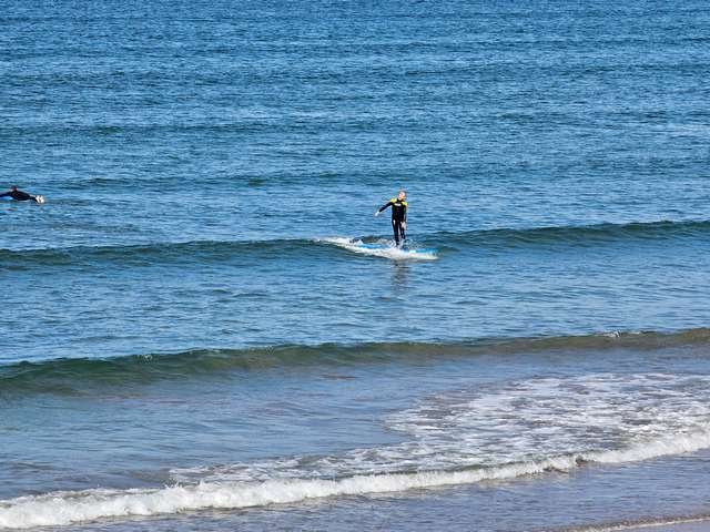 Surfer riding a knee high wave in front of the shop